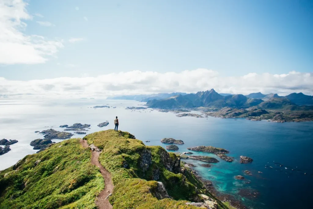 A man standing on a mountain looking out at the ocean